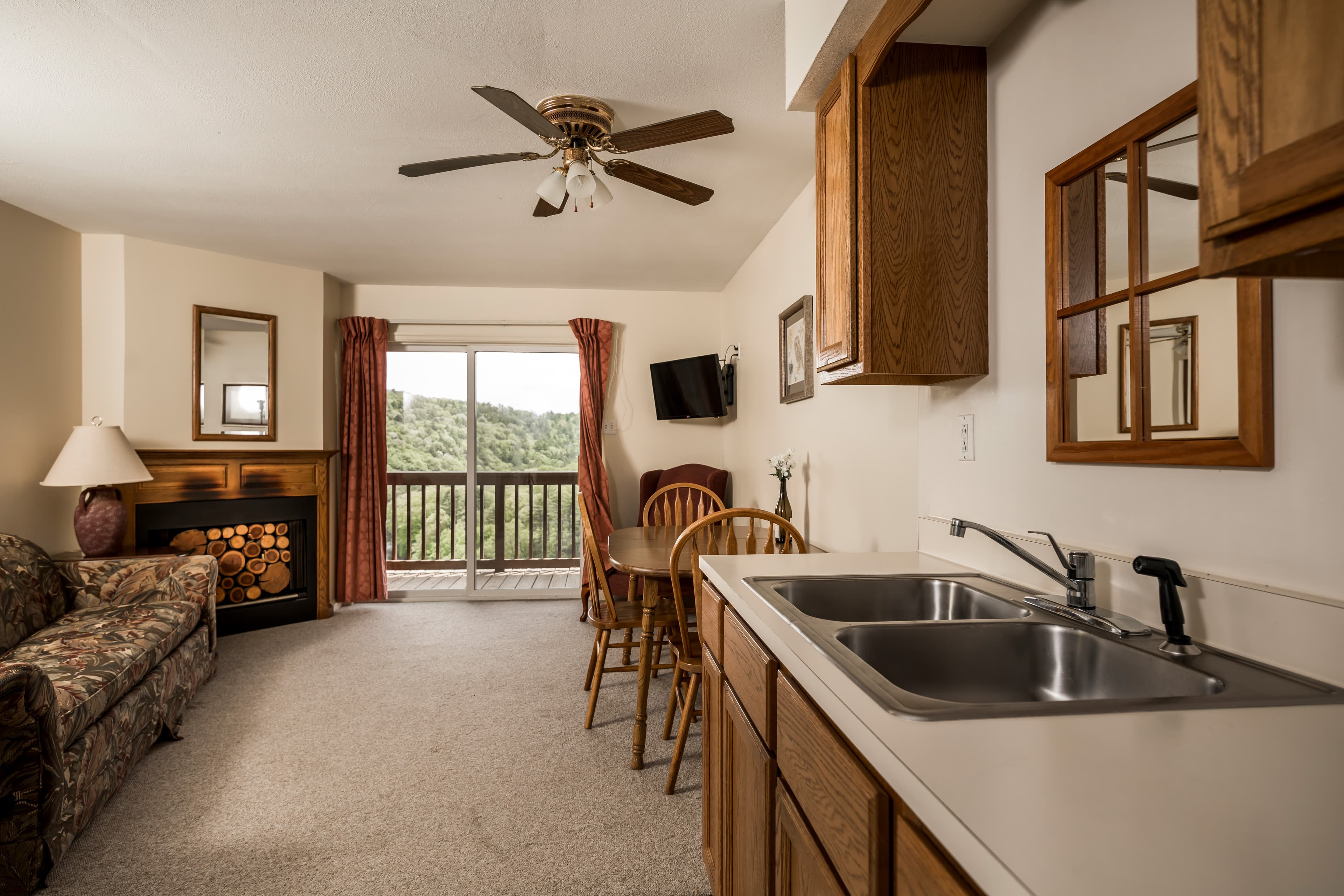 View to living room and sliding glass doors to deck taken from within kitchen in typical family suite, showing kitchen counters and sink on right side