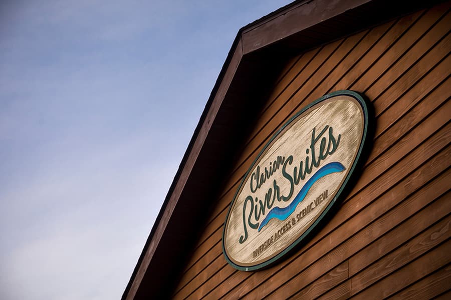 Sign for Clarion River Suites mounted on a wooden building.