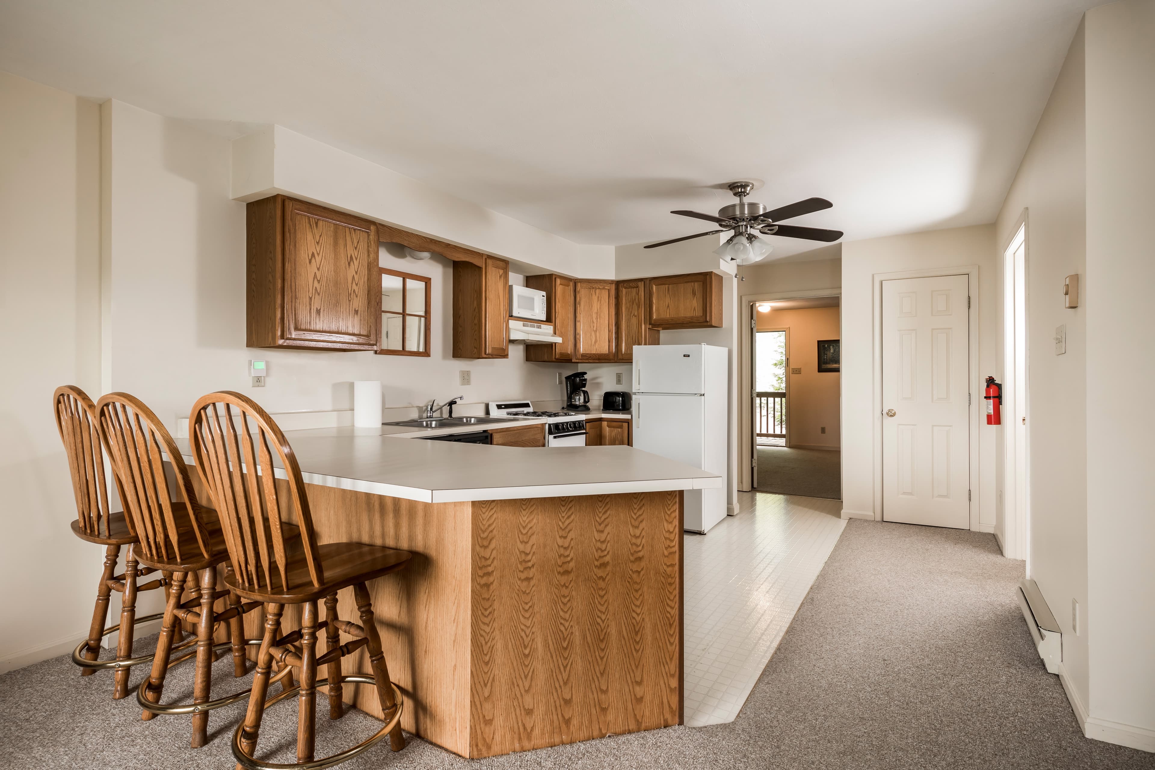 Bright kitchen with wooden cabinets, a central island with bar stools, and an open layout.