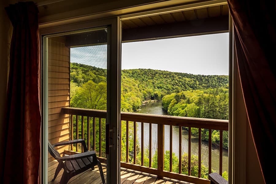 View from a balcony overlooking a river surrounded by lush greenery.