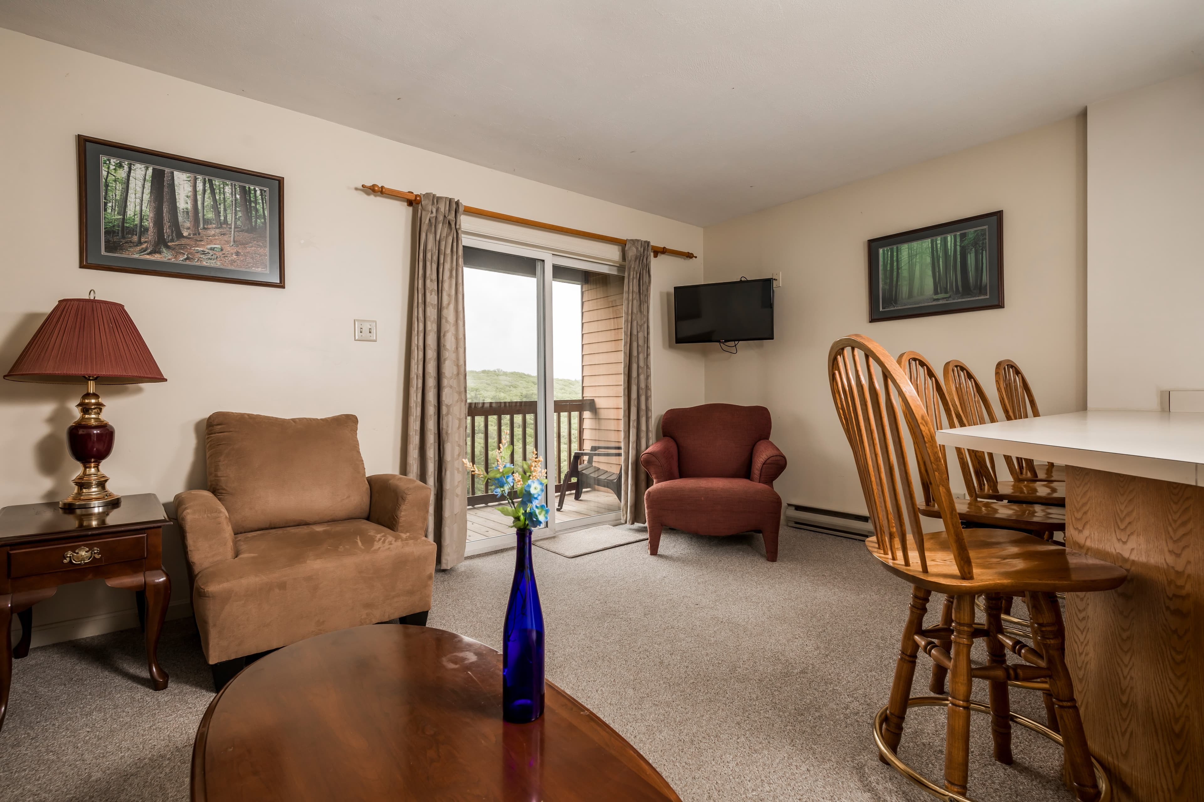 Cozy living area with seating, a TV, and a view of a balcony.