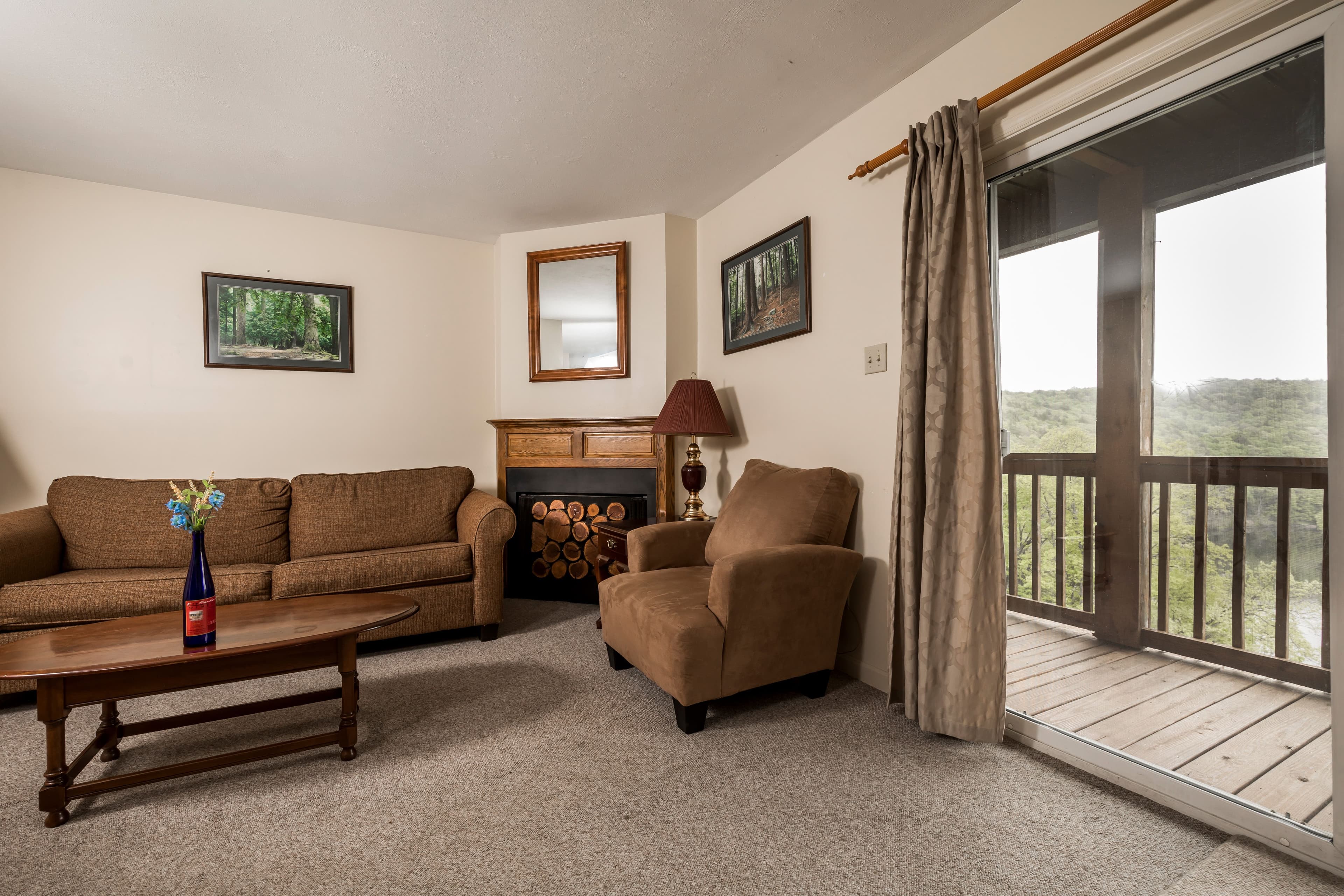 Cozy living area featuring a sofa, armchair, coffee table, and a sliding glass door to a balcony with scenic views.