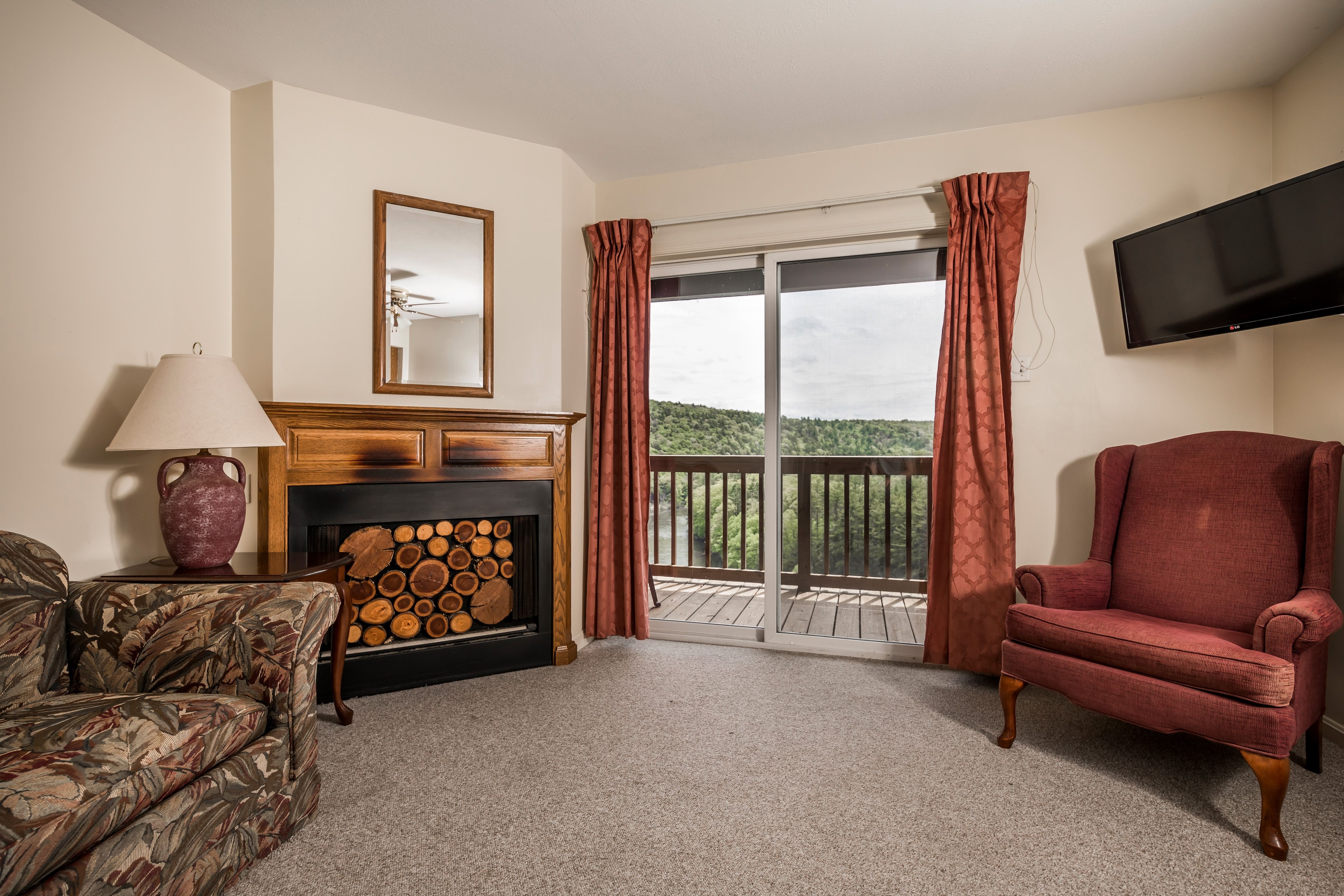 Cozy hotel room featuring a fireplace, chair, and balcony with a view of the outdoors.
